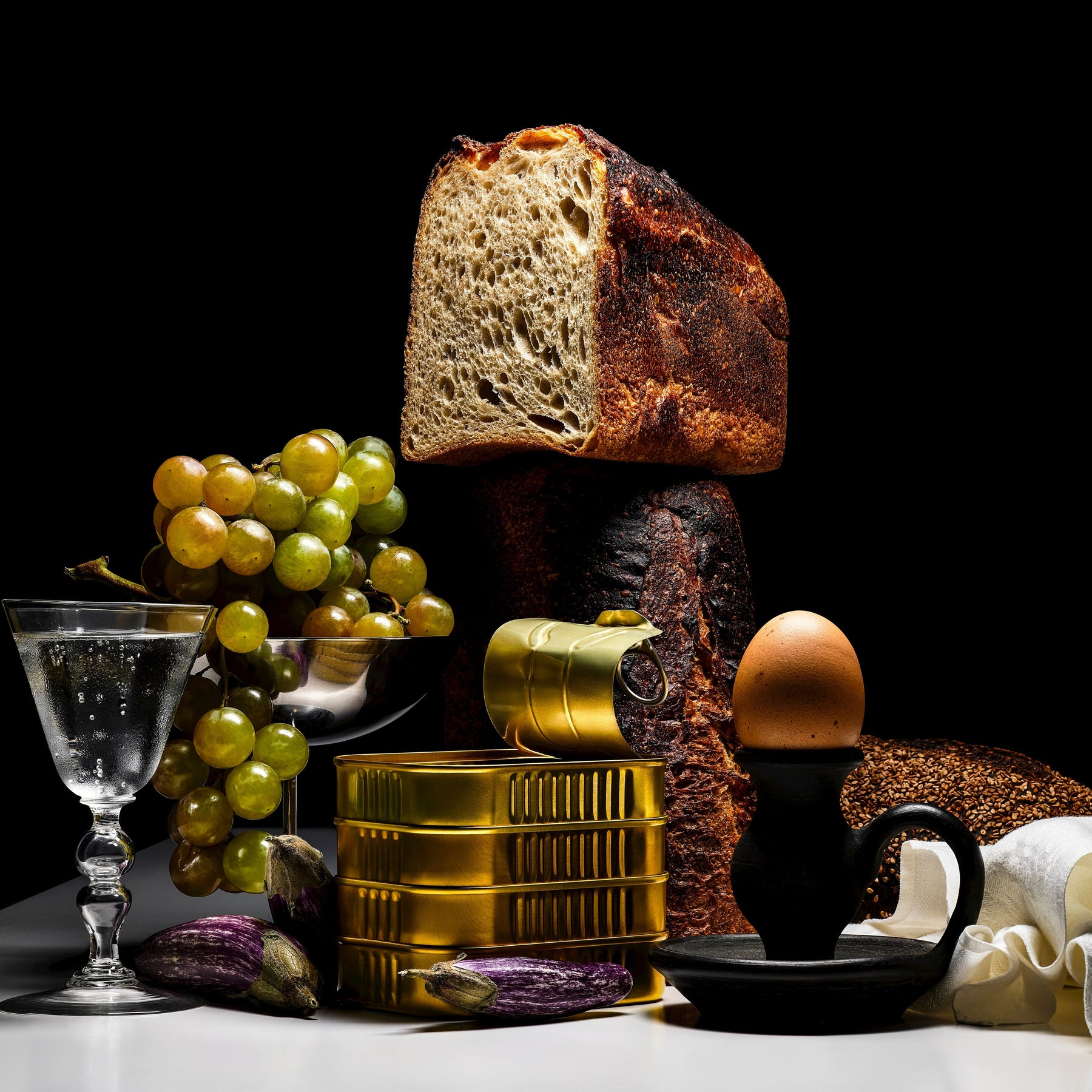 Still life with bread, grapes, and cod on a dark background